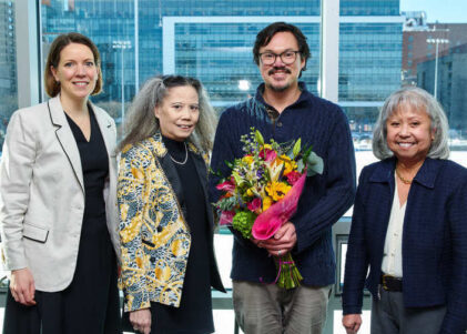 Three women and one man posing together